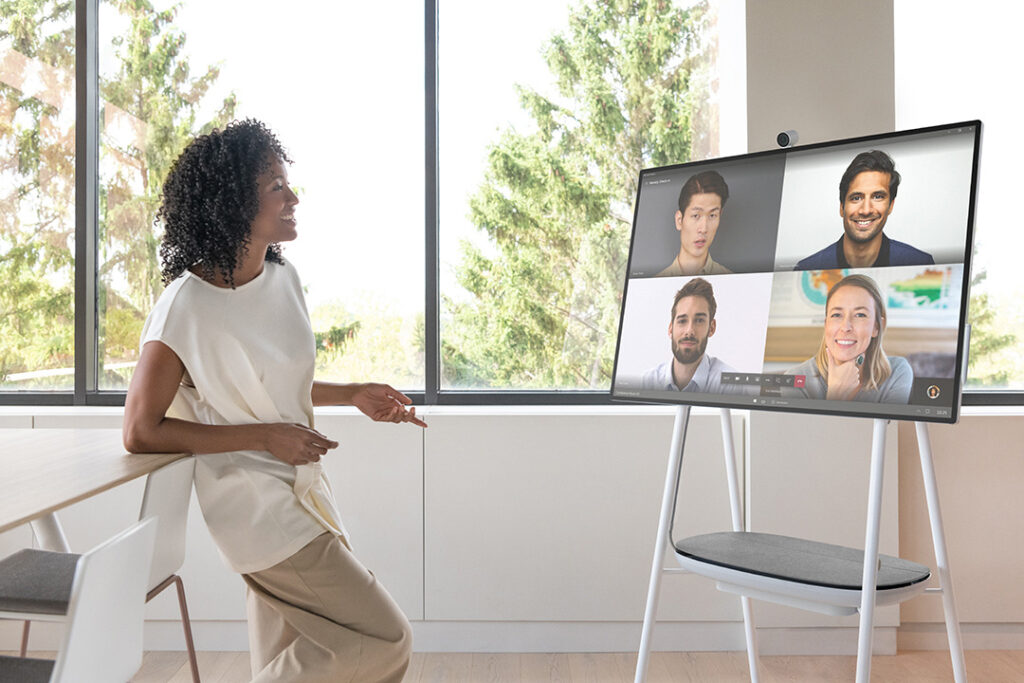 Hybrid workplace uses Microsoft Surface Hub to connect with remote workers in corporate conference room.