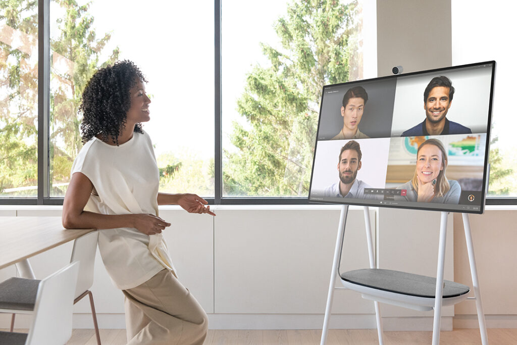 Hybrid workplace uses Microsoft Surface Hub to connect with remote workers in corporate conference room.