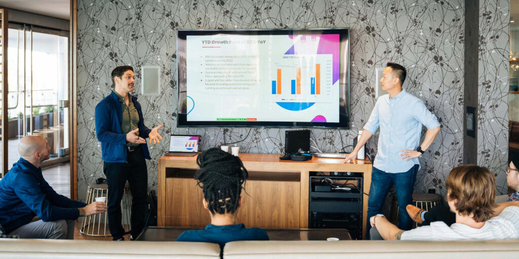 Corporate team utilizes USB-C connection to present laptop slideshow onto a television monitor.