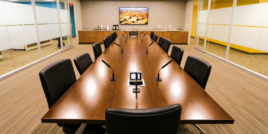 Corporate board room utilizes microphones and displays to enhance communication.